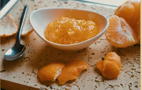 Puré de cítricos en un cuenco junto a fruta pelada